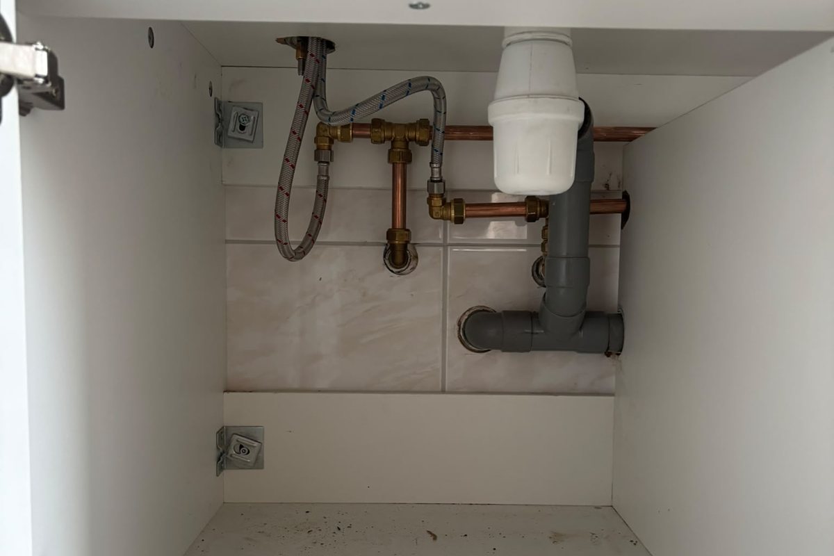 Sifon en koperen toevoerleidingen bij de afmontage van een nieuwe badkamer