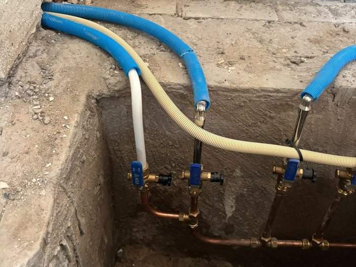 Nieuwe water- en rioolleidingen in een opengebroken vloer tijdens rioolwerkzaamheden