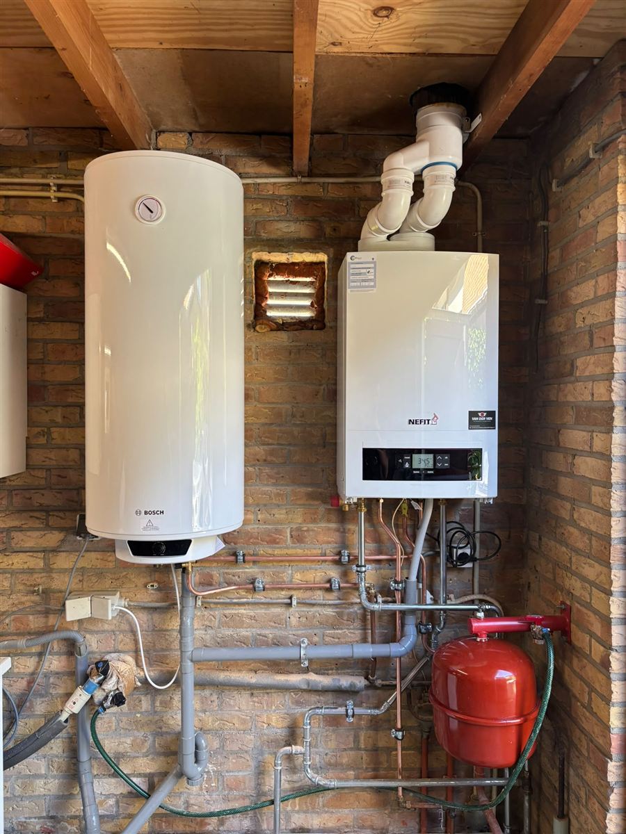 Nieuwe Nefit cv-ketel en elektrische boiler, strak gemonteerd op een gemetselde muur