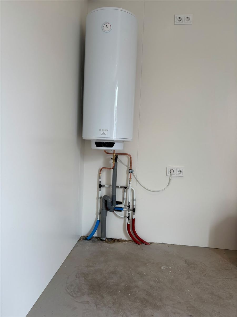 Nieuw aangelegde riool- en waterleidingen langs een muur tijdens een verbouwing